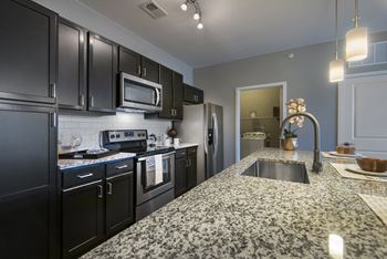 a kitchen with granite counter tops and black appliances  at Watermark at Harvest Junction, Longmont, Colorado